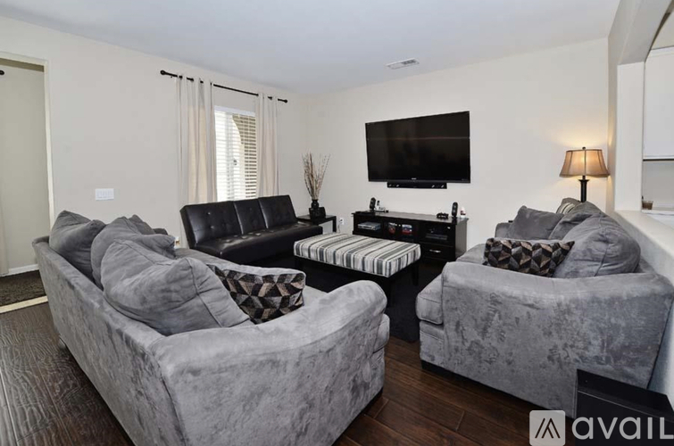 A living room with grey couches and a black leather chair.