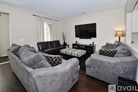 A living room with grey couches and a black leather chair.