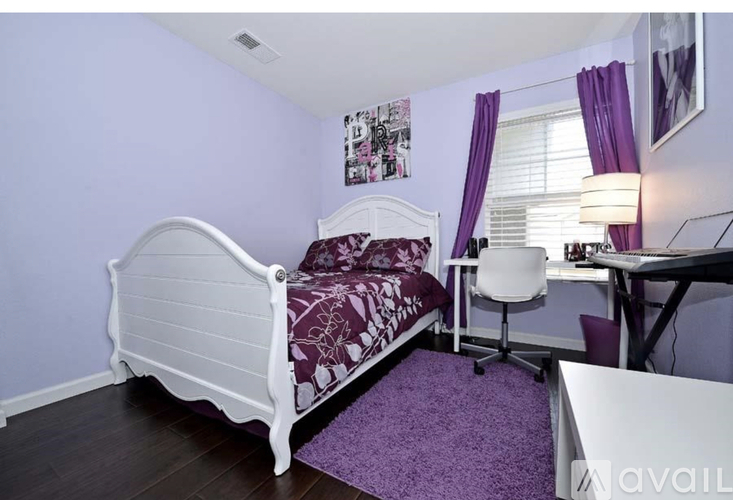 A bedroom with a white bed and purple accents.