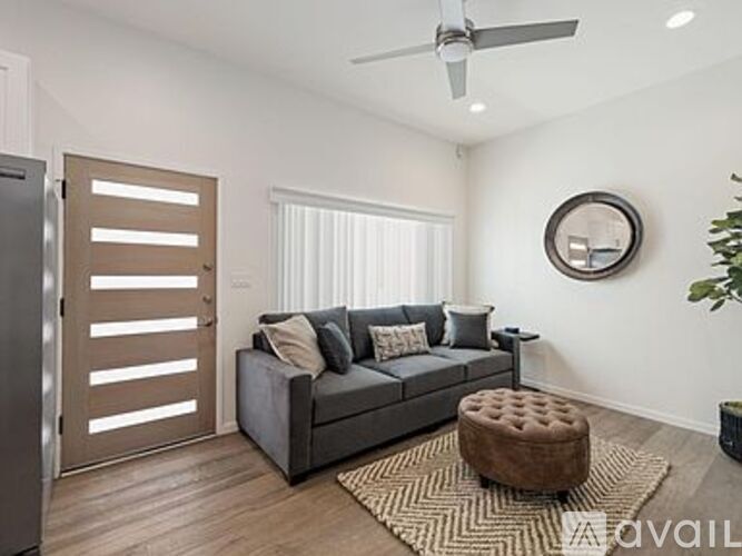A modern living room with a grey couch and a round mirror on the wall.