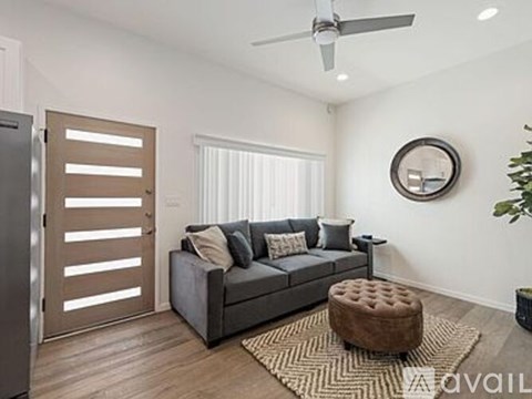A modern living room with a grey couch and a round mirror on the wall.