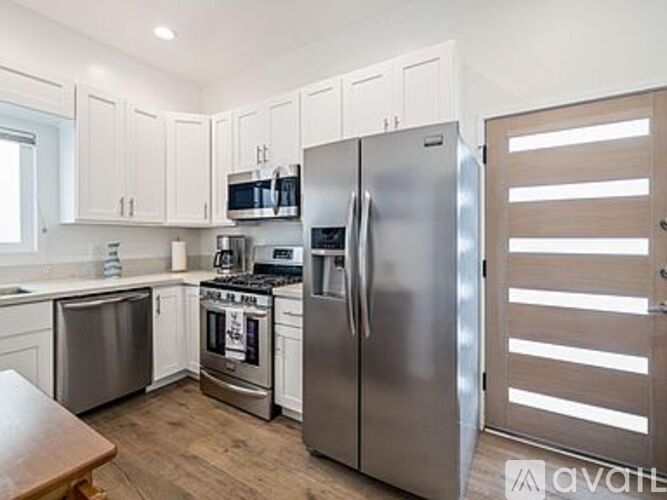 A kitchen with white cabinets and a stainless steel refrigerator.