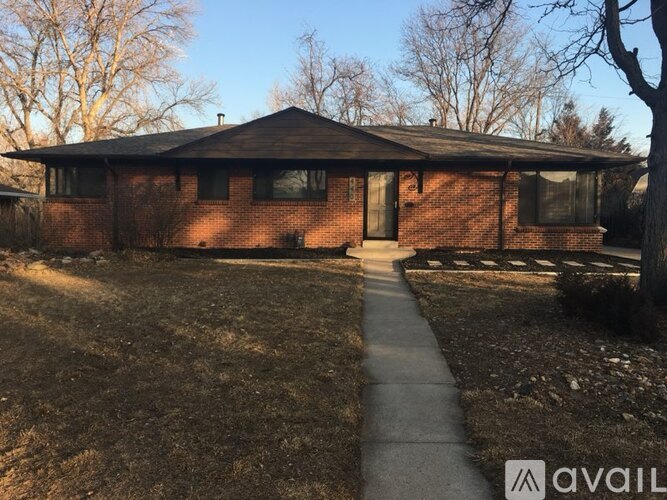 A house with a brick facade and a covered walkway leading to the front door.
