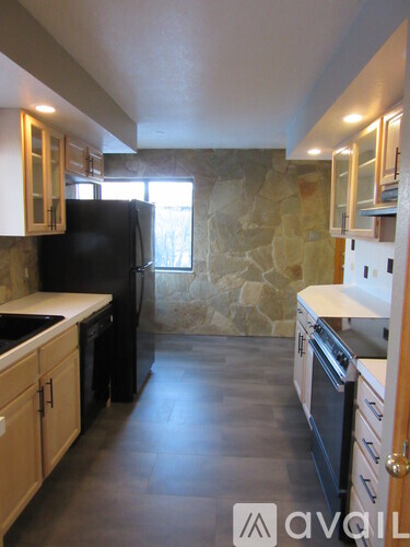 A kitchen with a black refrigerator and wooden cabinets.