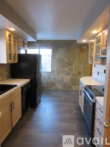 A kitchen with a black refrigerator and wooden cabinets.