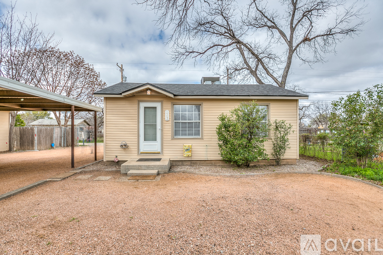 A small house with a gravel driveway in front.