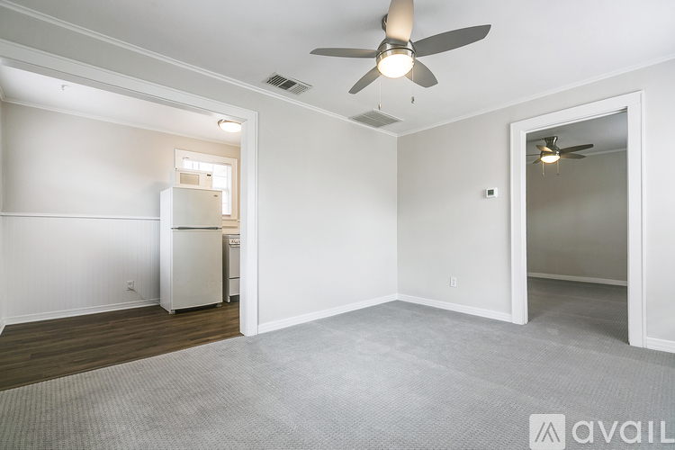 A room with a ceiling fan and a refrigerator in it.