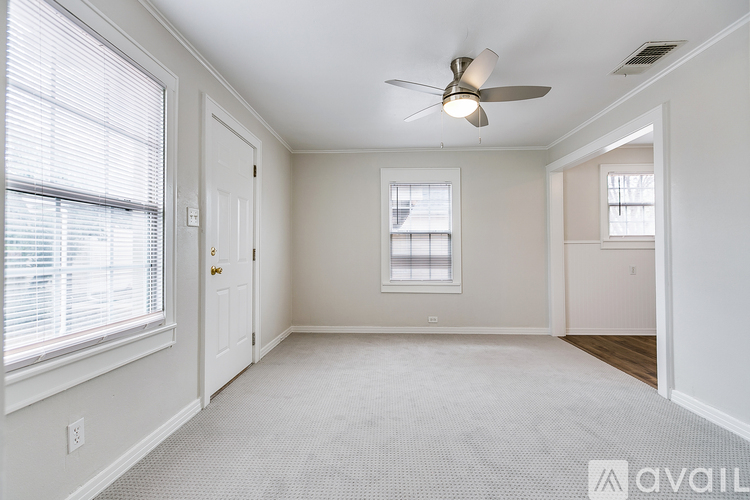 A spacious room with a ceiling fan and two windows.