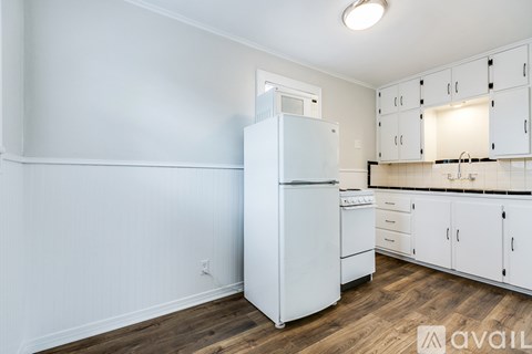 A white refrigerator is in a kitchen with white cabinets.
