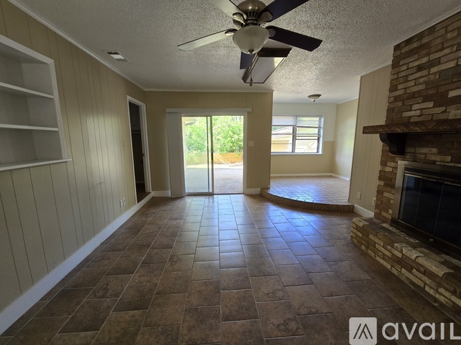 A living room with a fireplace and a ceiling fan.