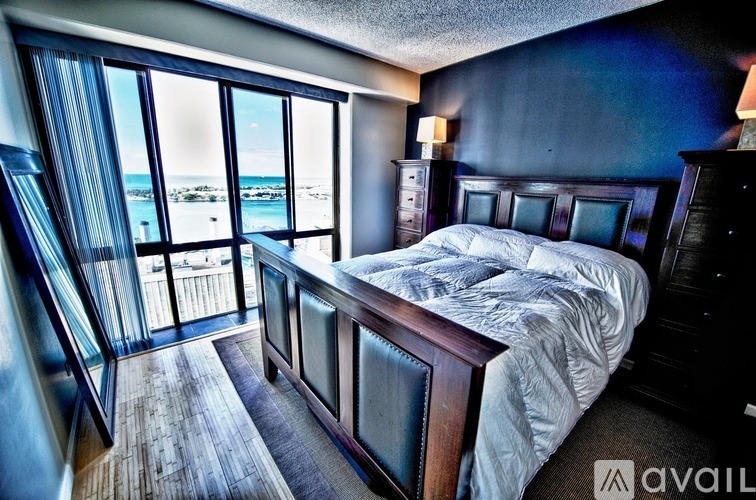 A bedroom with a large bed and a view of the beach through the window.