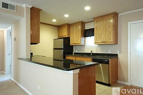A kitchen with wooden cabinets and black countertops.