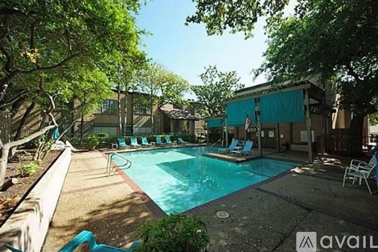 A pool surrounded by trees and chairs.