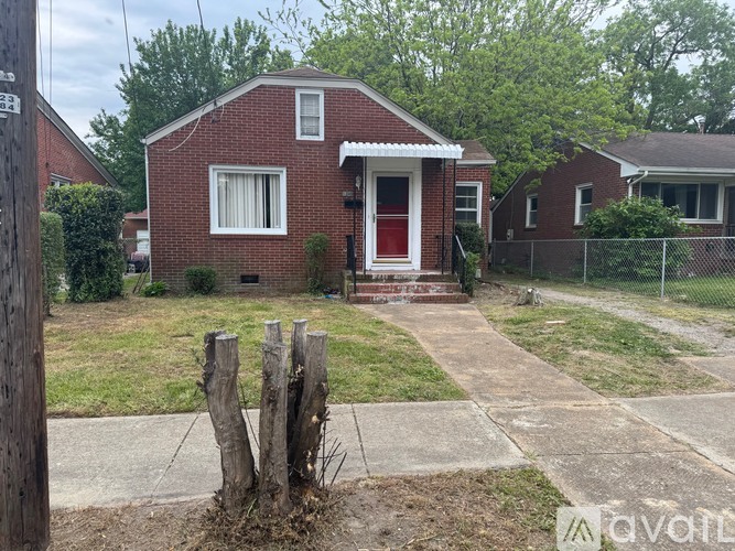 A red brick house with a white door and a small porch.