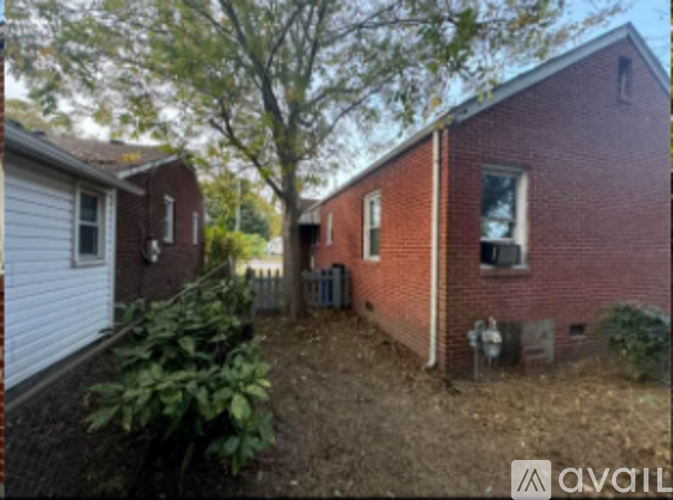 A red brick house with a white fence and a tree in front.