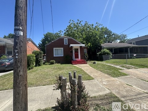 A red brick house with a white door and a red staircase leading to the door.