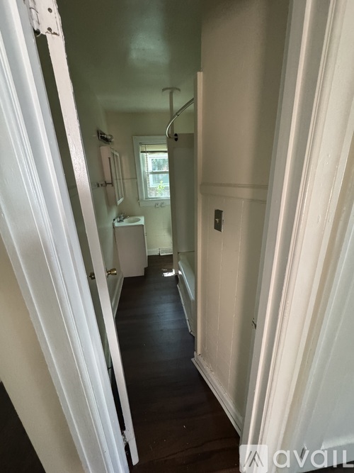 A narrow hallway with white walls and a wooden floor.