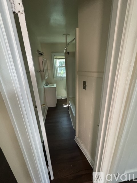 A narrow hallway with white walls and a wooden floor.