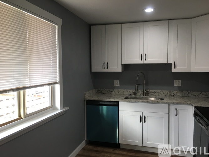 A kitchen with white cabinets and a marble countertop.