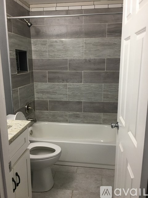 A bathroom with a toilet, tub, and tiled walls.