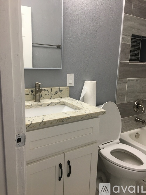 A bathroom with a toilet, sink, and mirror.
