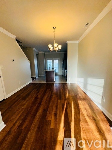 A spacious room with wooden flooring and a chandelier.