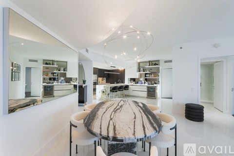 A modern kitchen with a large island and a dining table with a marble top.