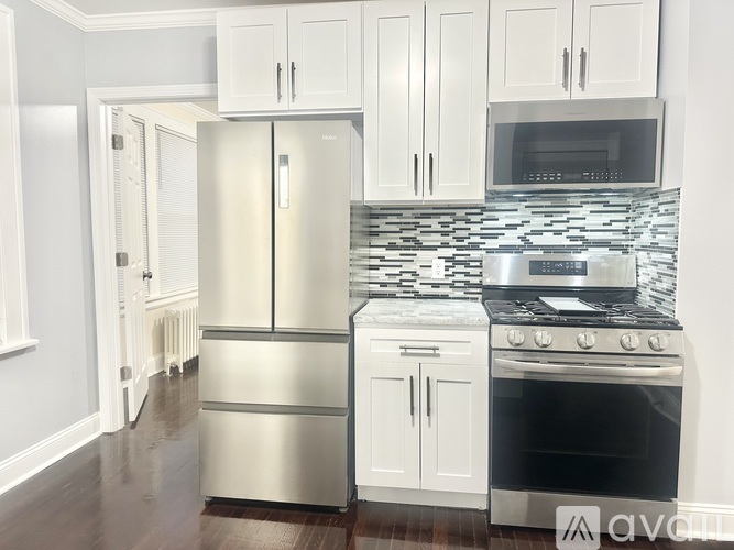 A kitchen with a stainless steel refrigerator and white cabinets.