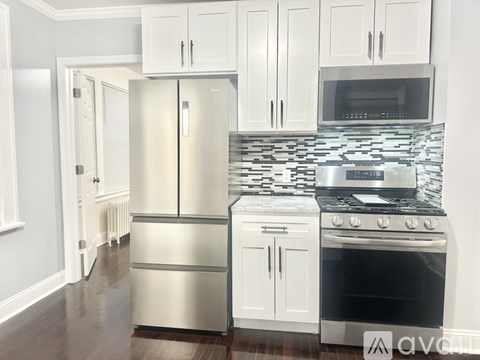A kitchen with a stainless steel refrigerator and white cabinets.