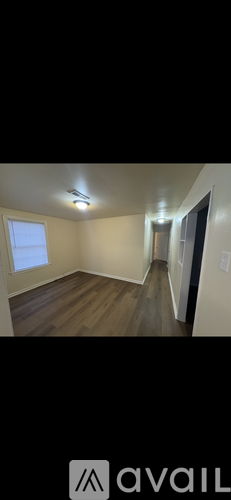 A room with wooden flooring and a window on the left side.