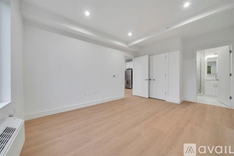 A spacious room with wooden flooring and white walls.