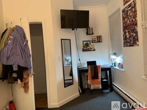 A room with a desk, chair, and a hanging closet.