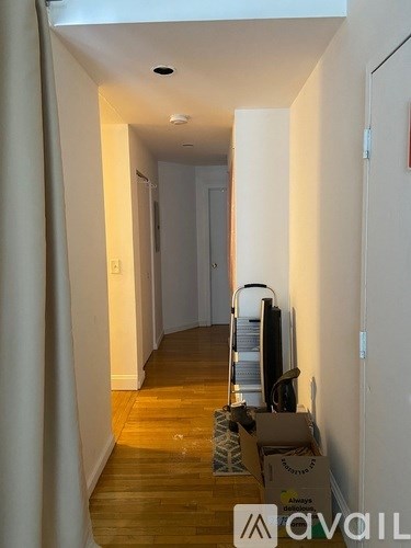 A hallway with a box on the floor and a staircase on the right.