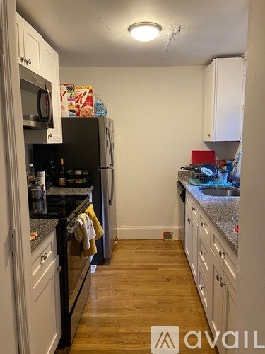 A kitchen with white cabinets and a black fridge.