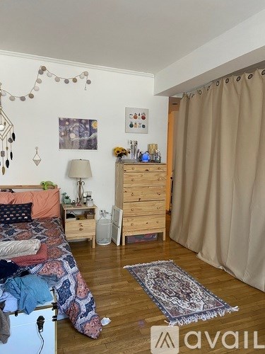 A bedroom with a bed, dresser, and a rug on the floor.