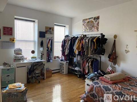 A room with a bed, a desk, and a closet full of clothes.