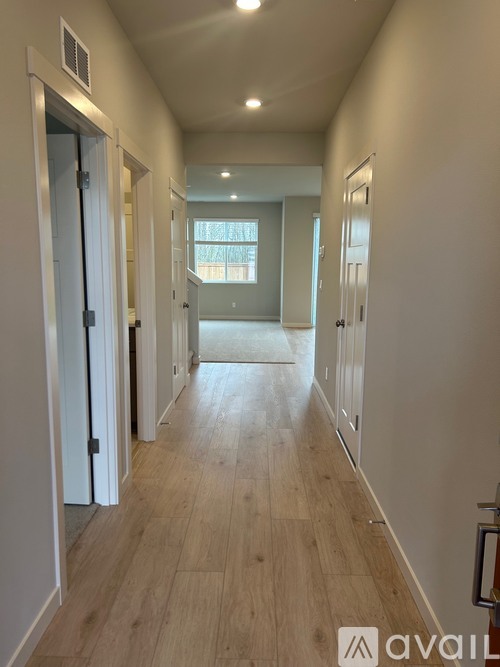 A long hallway with doors on both sides and a window in the distance.