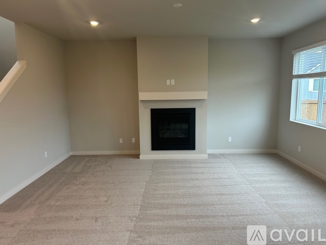A spacious living room with a fireplace and carpeted floor.