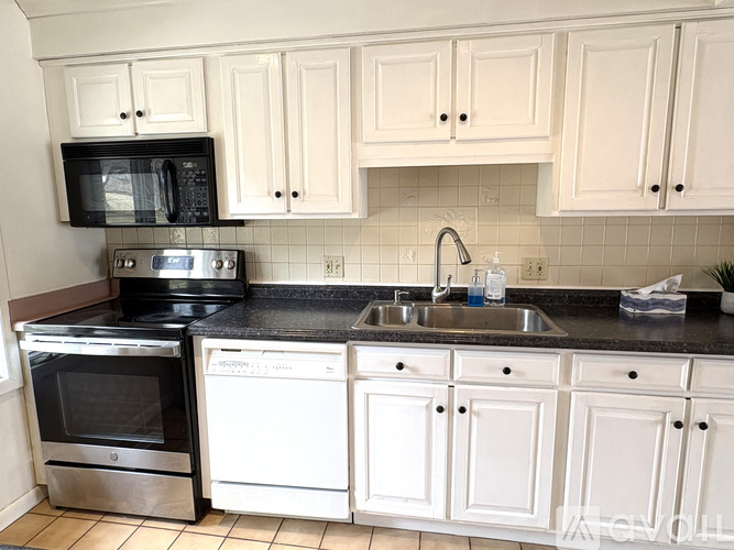A kitchen with white cabinets and black countertops.