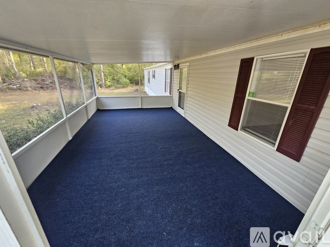 A room with a carpeted floor and a window with blinds.