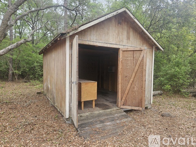 A wooden shed with a door open and a table inside.