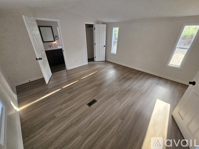 A spacious room with wooden flooring and a skylight.