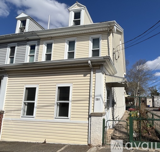 A two-story building with a white facade and a green gate in front.
