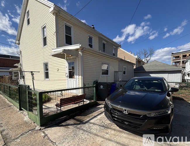 A black Honda car is parked in front of a two-story house.