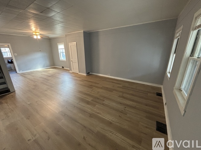 A spacious room with wooden flooring and a ceiling light fixture.