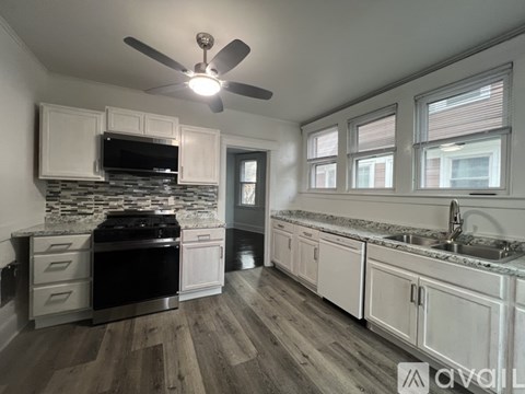 A modern kitchen with a black stove top oven and white cabinets.