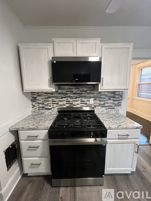 A kitchen with a black stove top oven and white cabinets.