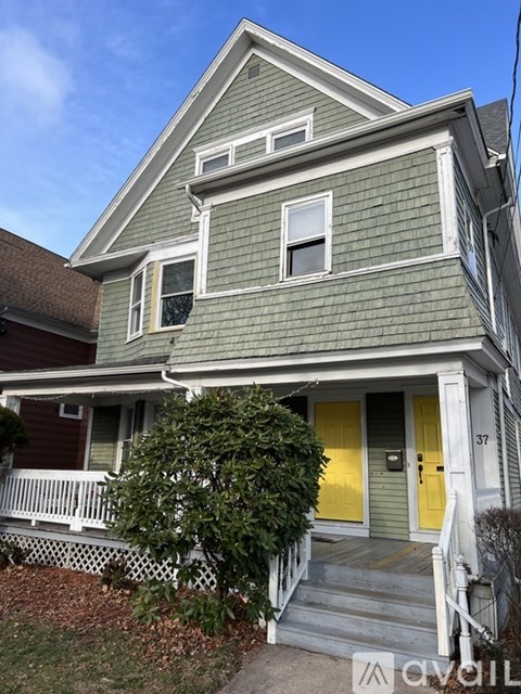 A two-story house with a yellow front door and white railings.