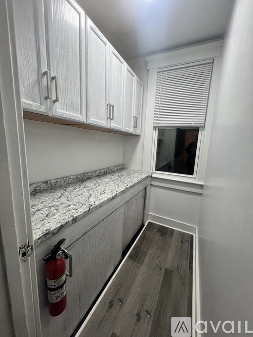 A white kitchen with a fire extinguisher on the door.