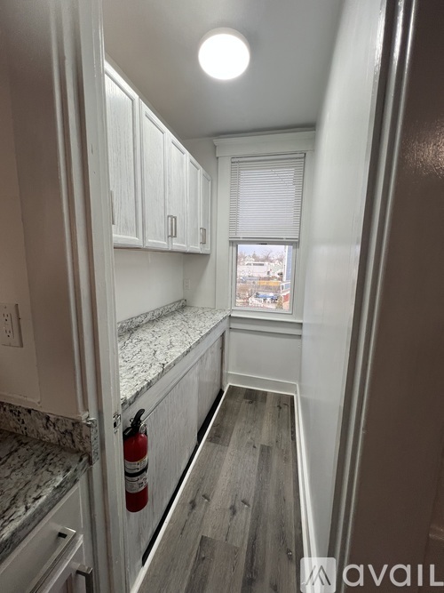 A kitchen with a marble counter top and white cabinets.